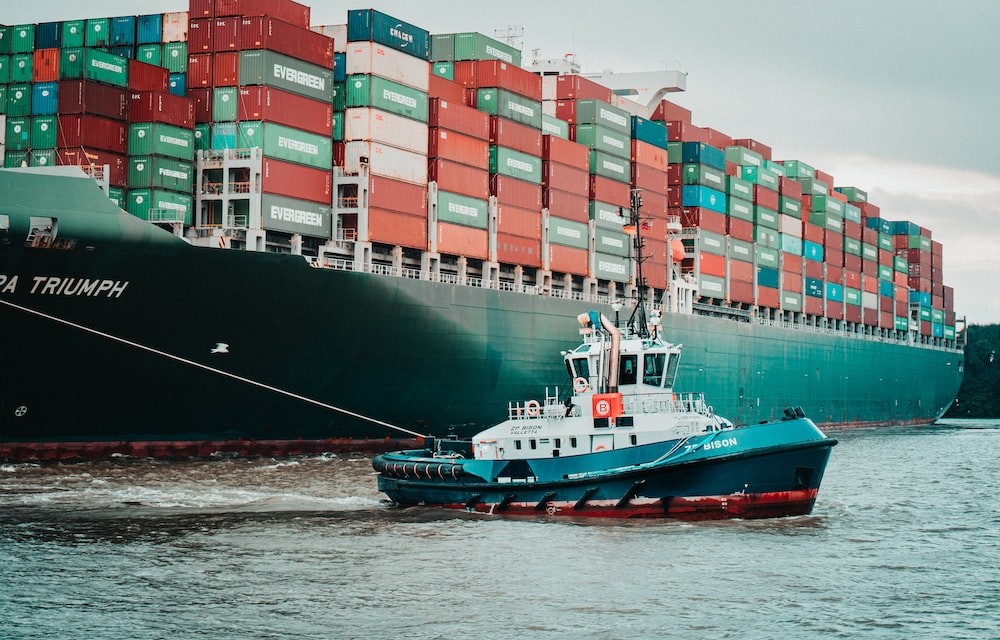 Tugboat guiding a large cargo ship loaded with shipping containers
